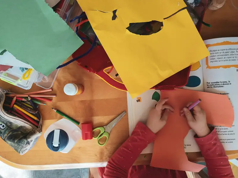 Manos de niños recortando papel de colores en un taller